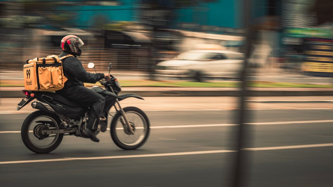 Hello world! Motorcycle deliveryman speeds through city streets, showcasing fast food service.