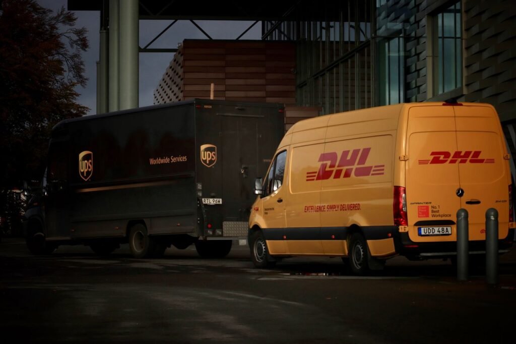 Mastering the First Impression: Your intriguing post title goes here DHL and UPS delivery trucks parked at night near a modern building, ready for logistics operations.